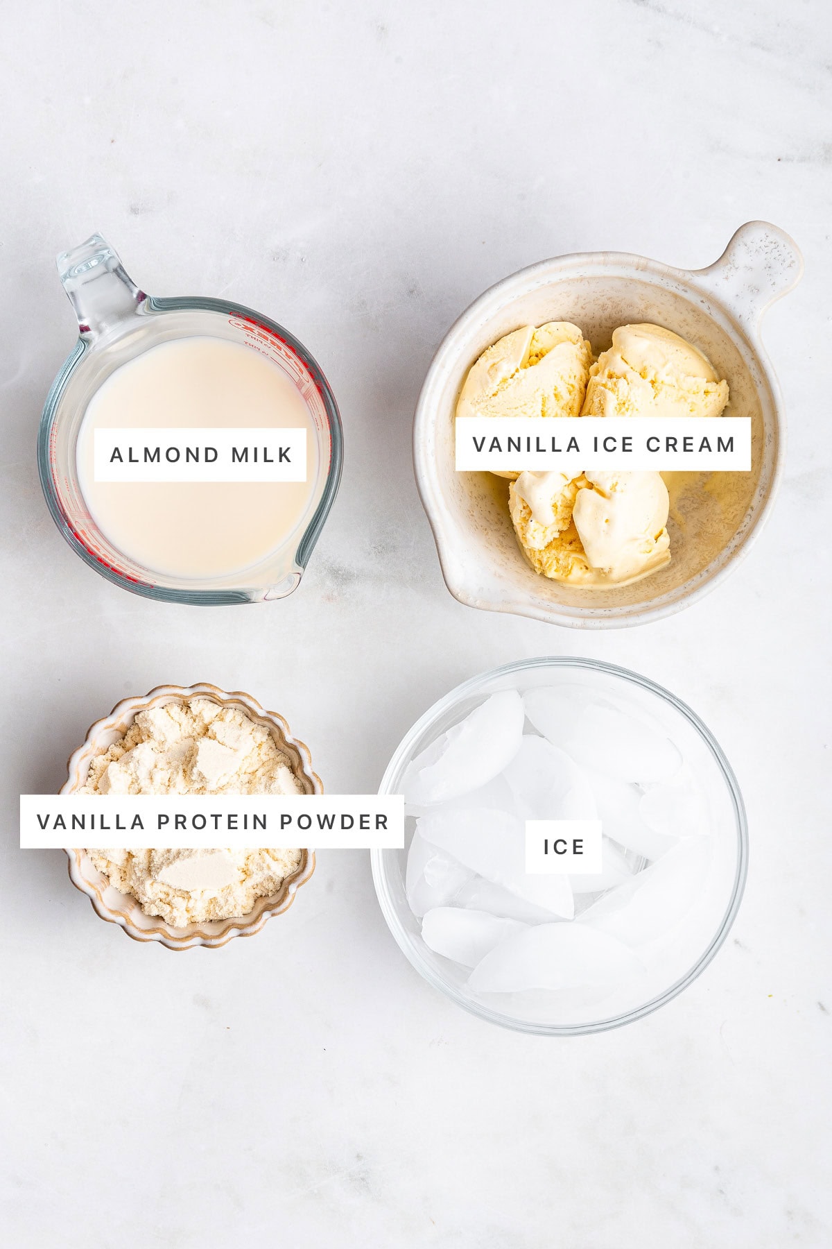 Ingredients measured out to make Protein Milkshake: almond milk, vanilla ice cream, vanilla protein powder and ice.