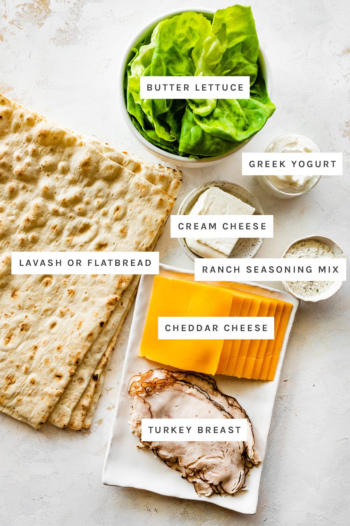 Ingredients measured out to make Turkey Pinwheel Sandwiches: butter lettuce, Greek yogurt, cream cheese, lavash/flatbread, ranch seasoning mix, cheddar cheese and turkey breast.